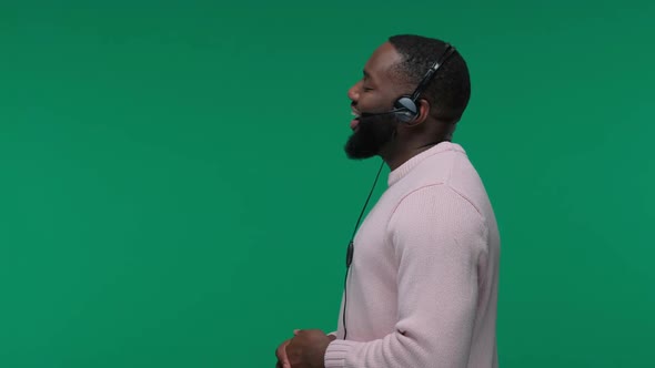 Smiling African American Man Wearing Wireless Headset Talking To Microphone Isolated on Green Screen