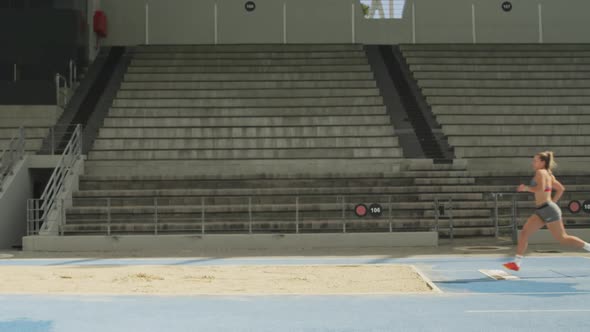 Side view of caucasian athlete doing long jump