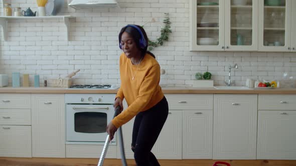 Happy Teenage Girl Enjoying Music During Vacuuming Indoors