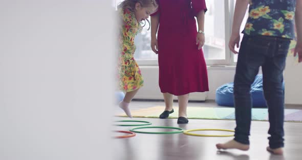 Small Nursery School Children with Female Teacher on Floor Indoors in Classroom Doing Exercise