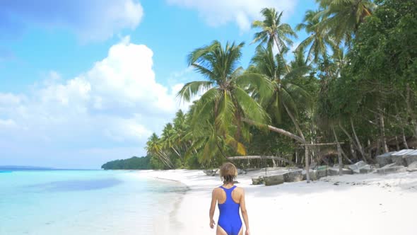 Slow motion: woman sunbathing walking on white sand beach turquoise water tropic
