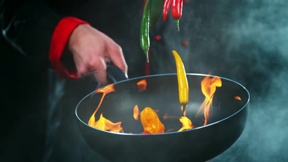 Super Slow Motion Shot of Chef Holding Frying Pan and Falling Chilli Peppers Into Fire at 1000Fps