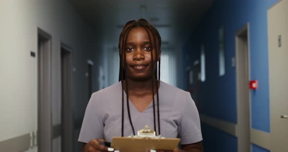 A Doctor Stands in the Hospital Corridor and Looks at Camera Smiling