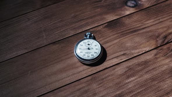 An Antique Stopwatch Lies on Wooden Table and Counts the Seconds Timelapse