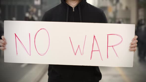 Unknown Activist Holds a Placard with NO WAR Text