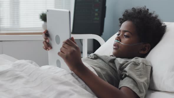 Child Using Tablet in Hospital Bed