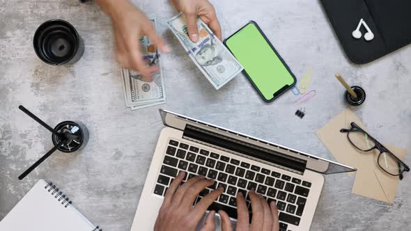 Woman counting dollar bills money, man working on laptop computer