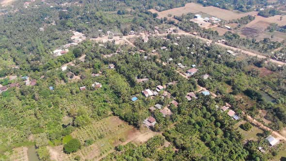 Aerial view of Battambang Cambodia on a clear dry summer day showing trees houses and empty fields