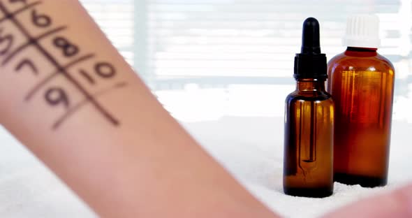 Doctor holding medicine dropper over a hand of patient with number grid