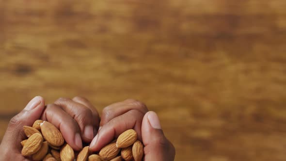 Video of almonds in the hands on wooden background