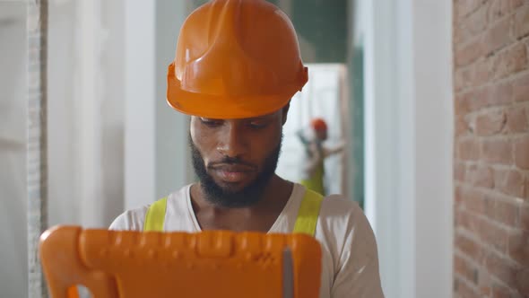 African Construction Worker at Site Using Digital Tablet Checking Plan of Renovation