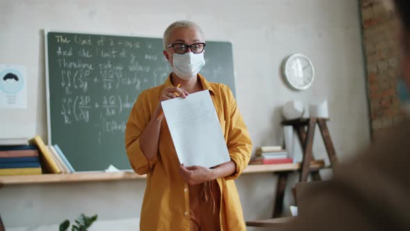 Female Teacher in Mask Talking with Student on Lesson