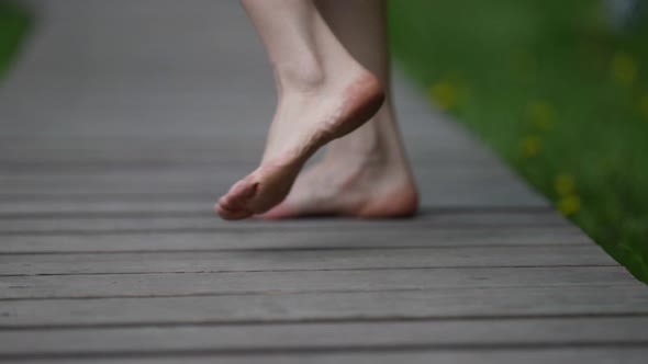 Female Bare Feet Walk Along a Wooden Path and Bounce