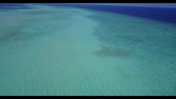 Aerial above panorama of idyllic tourist beach adventure by blue lagoon with white sandy background 