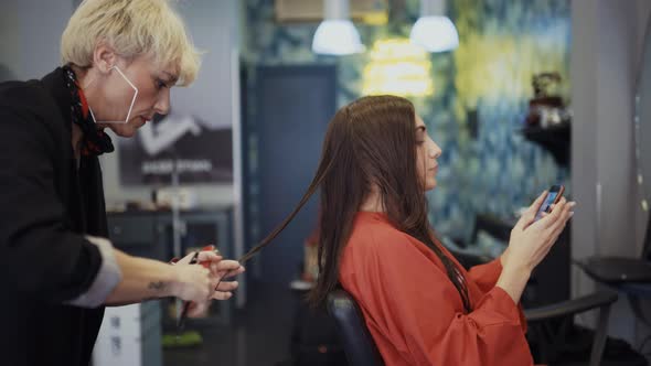 Young woman with mobile phone in hairdressing salon