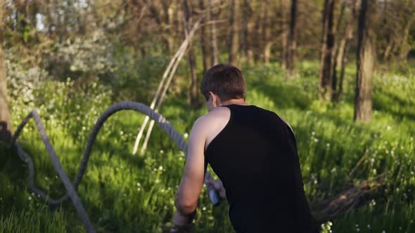 Sports Man is Training with Undulating Ropes