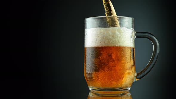 Super Slow Motion Shot of Pouring Fresh Beer Into Glass on Black Background at 1000Fps.