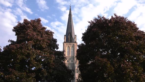 Church steeple centred between trees.