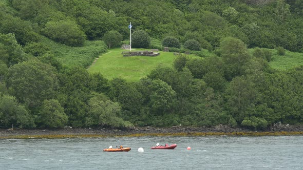 Inflatable boats anchored near a green hill