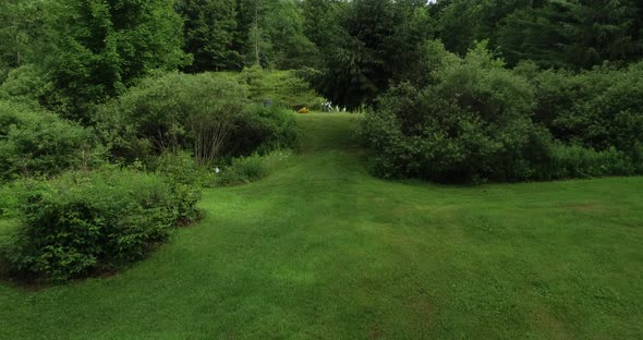 A low drone flight over a freshly mowed field rising to reveal a private fishing pond in upstate New