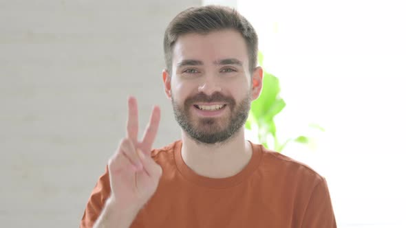 Young Man Showing Victory Sign with Finger
