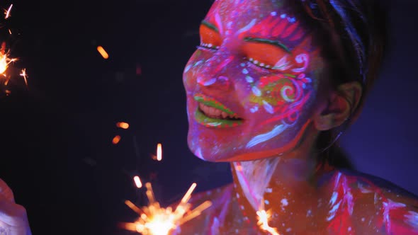 Woman with UV Drawings with Sparklers Under the Light of Fluorescent Lamps