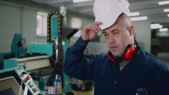 A Male Factory Worker Puts on a Safety Helmet