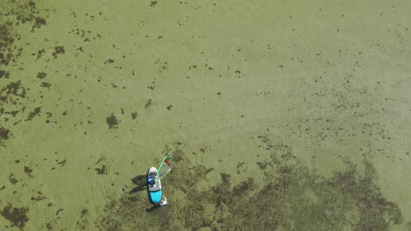 Aerial Drone Footage of Windsurf Instructor Teaching Woman Beginner To Standing on Surfboard