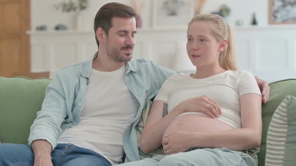 Talking Pregnant Woman Relaxing with Husband at Home