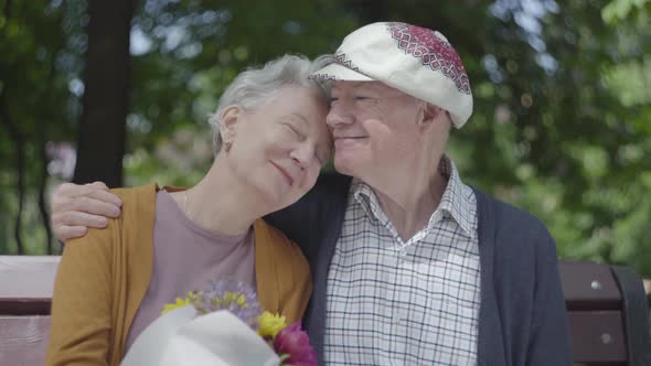 Portrait of a Mature Couple in Love Sitting on a Bench in the Park