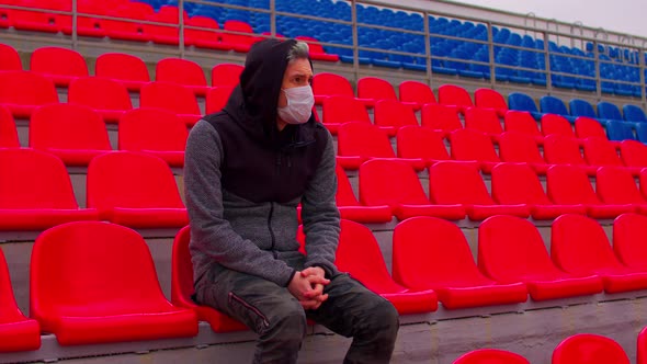 Young Man in Medical Mask Sitting on Stadium Bleachers Alone