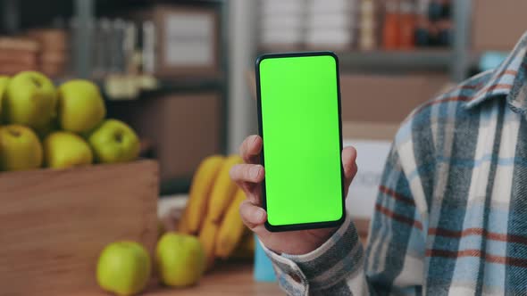 Food Bank Worker Holding Smartphone with Mock Up Screen