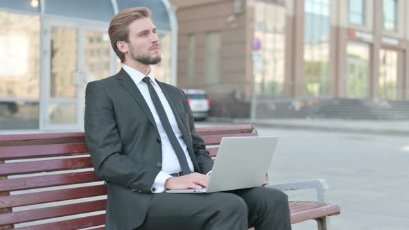 Thinking Businessman Using Laptop While Sitting Outdoor on Bench