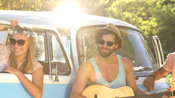 Hipster friends playing music and standing next to the van