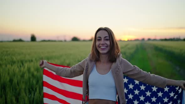 Happy Young Woman Holding Usa United States Flag Outdoor After Sunset with Polica Lights on Face