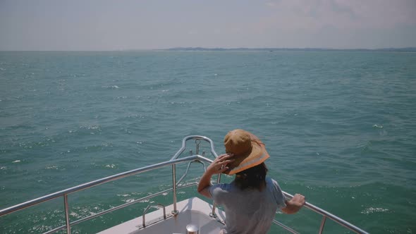 Happy Young Tourist Woman Holds Her Hat on Cruise Yacht Boat Nose Enjoying Perfect Windy Sunny Sea