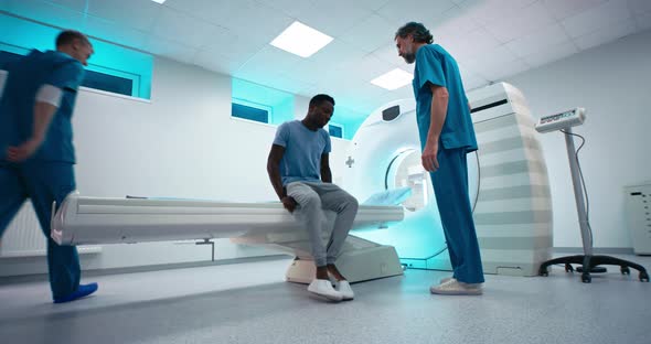 Male Doctors Inviting Black Man To CT Scanning Procedure