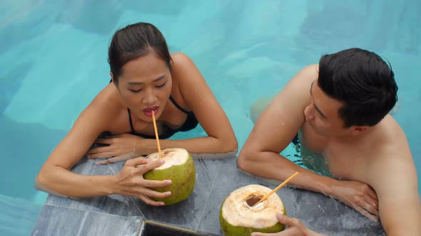 Asian Couple Drinking Cocktails in Pool