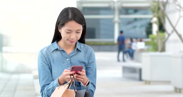 Asian Woman use of mobile phone for shopping with holding shopping bag