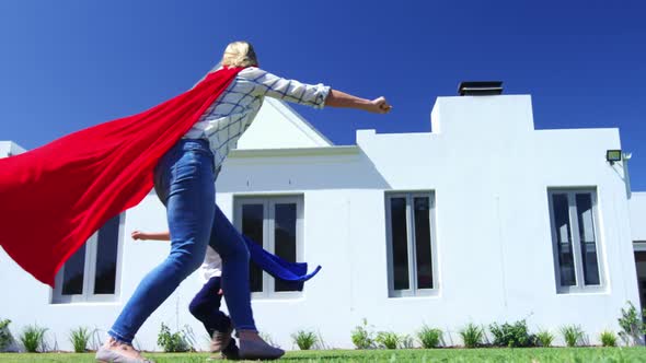 Mother and son in superhero costume having fun in garden 4k