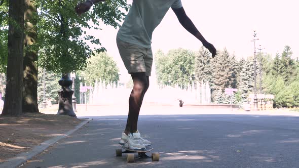 Happy African American Man in a Cap with a Running Start Gets Up on a Skateboard and Starts Riding