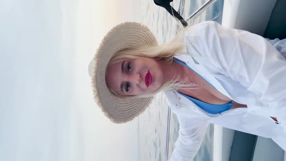 Young beautiful caucasian woman in a white shirt with a fedora hat sitting on the boat. Happy female