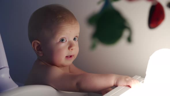 Baby Boy Standing in White Wooden Crib in the Evening Face of Happy Baby Boy in Light of Night Lamp