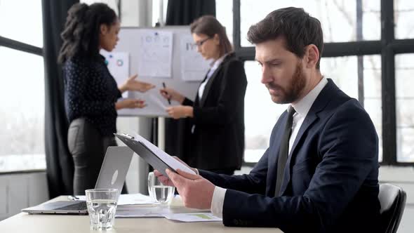 Successful Business Man Company Ceo Sits in the Office During Corporate Brainstorm Looks at Camera