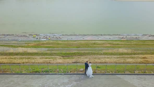 Newlywed Couple Looks at River From Embankment Upper View