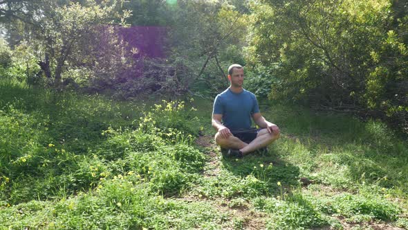 A handsome man in a green grassy forest meadow in nature on a bright sunny day thinking about life i