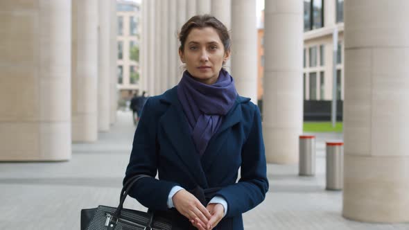 Portrait of Serious Beautiful Businesswoman Wearing Coat and Scarf Looking at Camera Outdoors