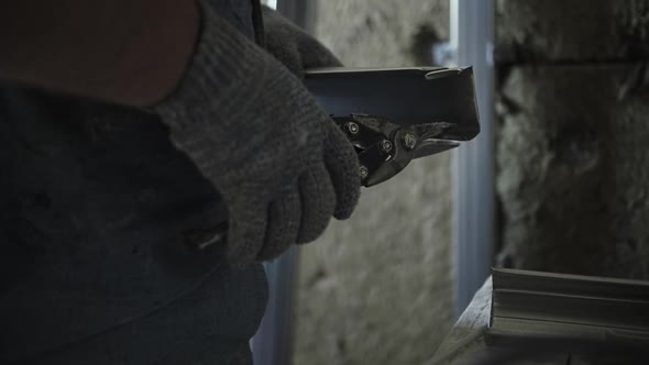 worker cuts metal profile with scissors