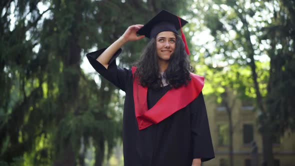 Portrait of Confident Happy Graduate Student Throwing Mortarboard Cap Up Laughing