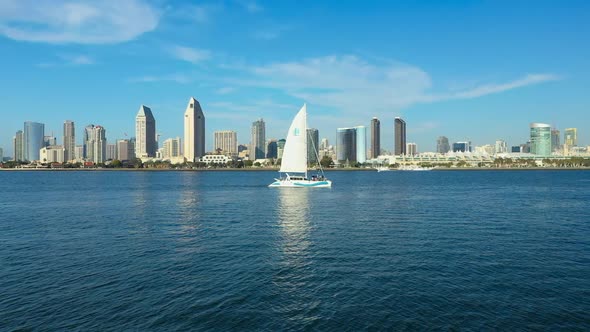 Aerial view of a sail boat on San Diego Bay with the San Diego city skyline in the background